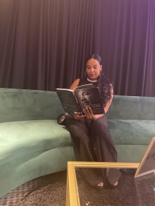 Brittney sitting on a green couch reading a book.