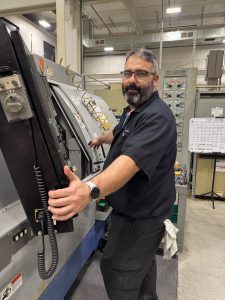 Ken operating a machine in a manufacturing facility as part of his apprenticeship journey