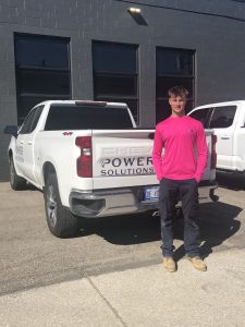 Alex smiles while standing beside a Power Solutions Group work truck.